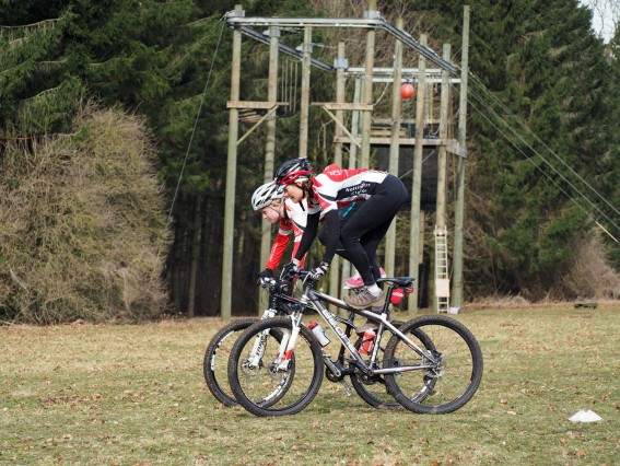 Two women performing skills while mountain biking