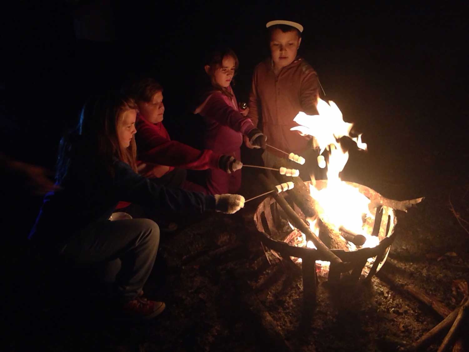 Pupils around a campfire (onsite ground-based) with marshmallows at Thornbridge Outdoors