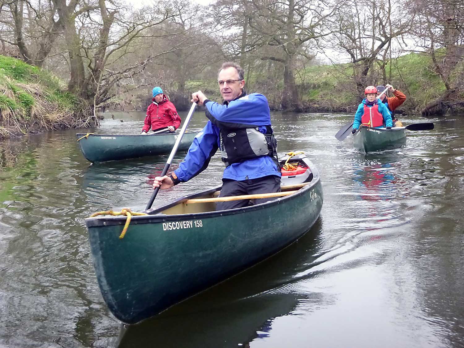 Adults canoeing along a river