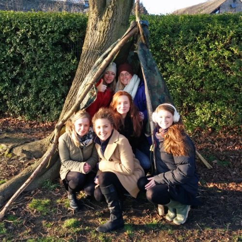 Teachers in a den made within the school grounds on a CPD course