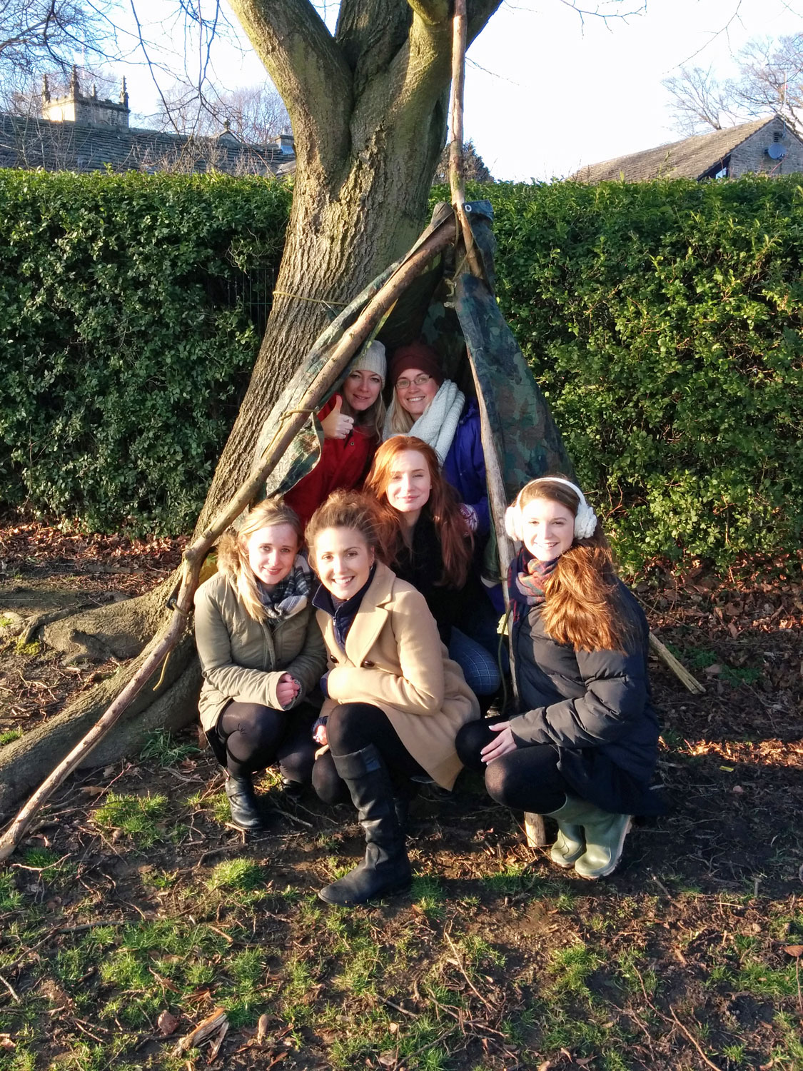Teachers in a den made within the school grounds on a CPD course