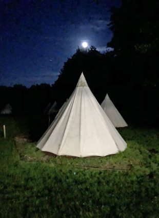 Teepee at nighttime with the moon in the sky