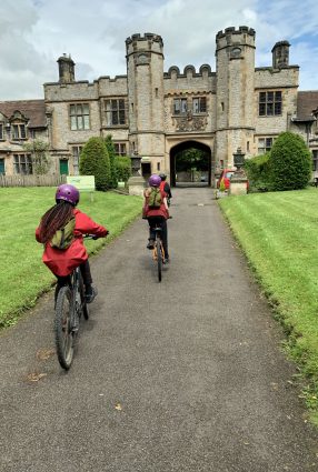 Children ride bikes up the driveway entrance to Thornbridge Outdoors