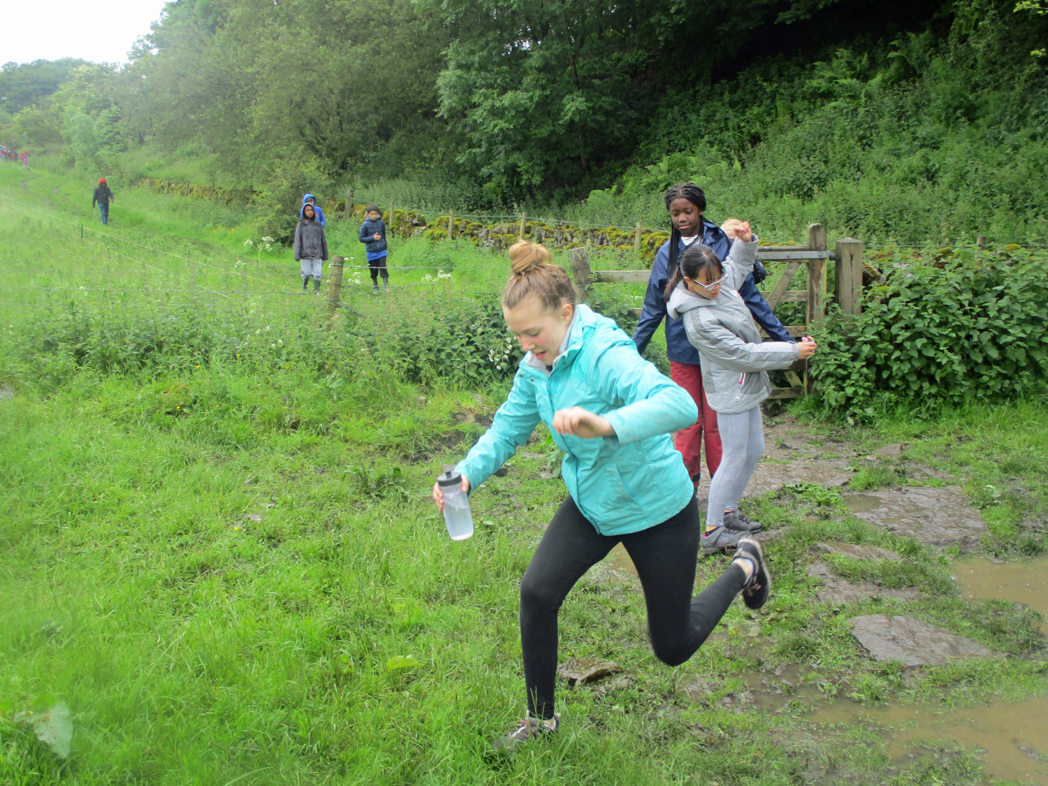 Students leap over puddles on a local walk in the Peak District