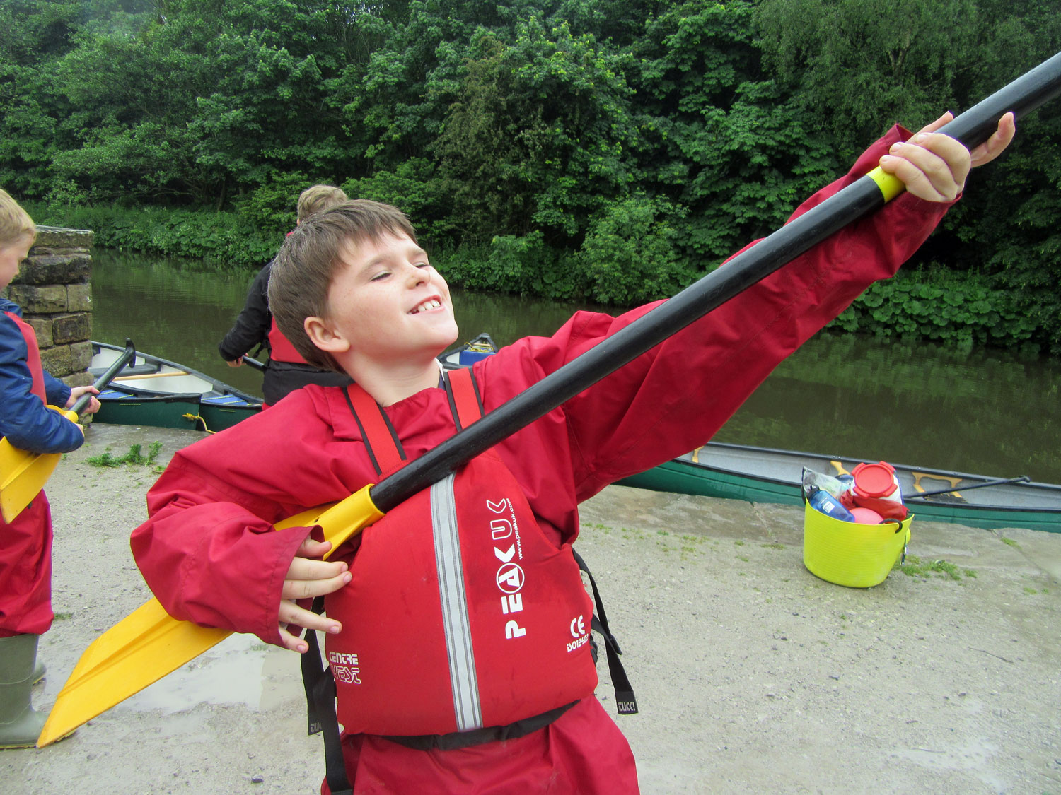 A school boy strums his canoe paddle as if it were an air guitar