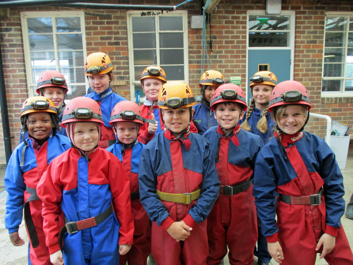 Students stand for a group photo wearing their caving suits and helmets with headtorches