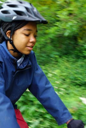 School girl rides bicycle in the grounds of Thornbridge Outdoors