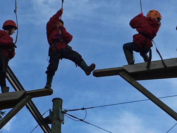 Child takes a big step across the leap of faith up the Sky Ropes