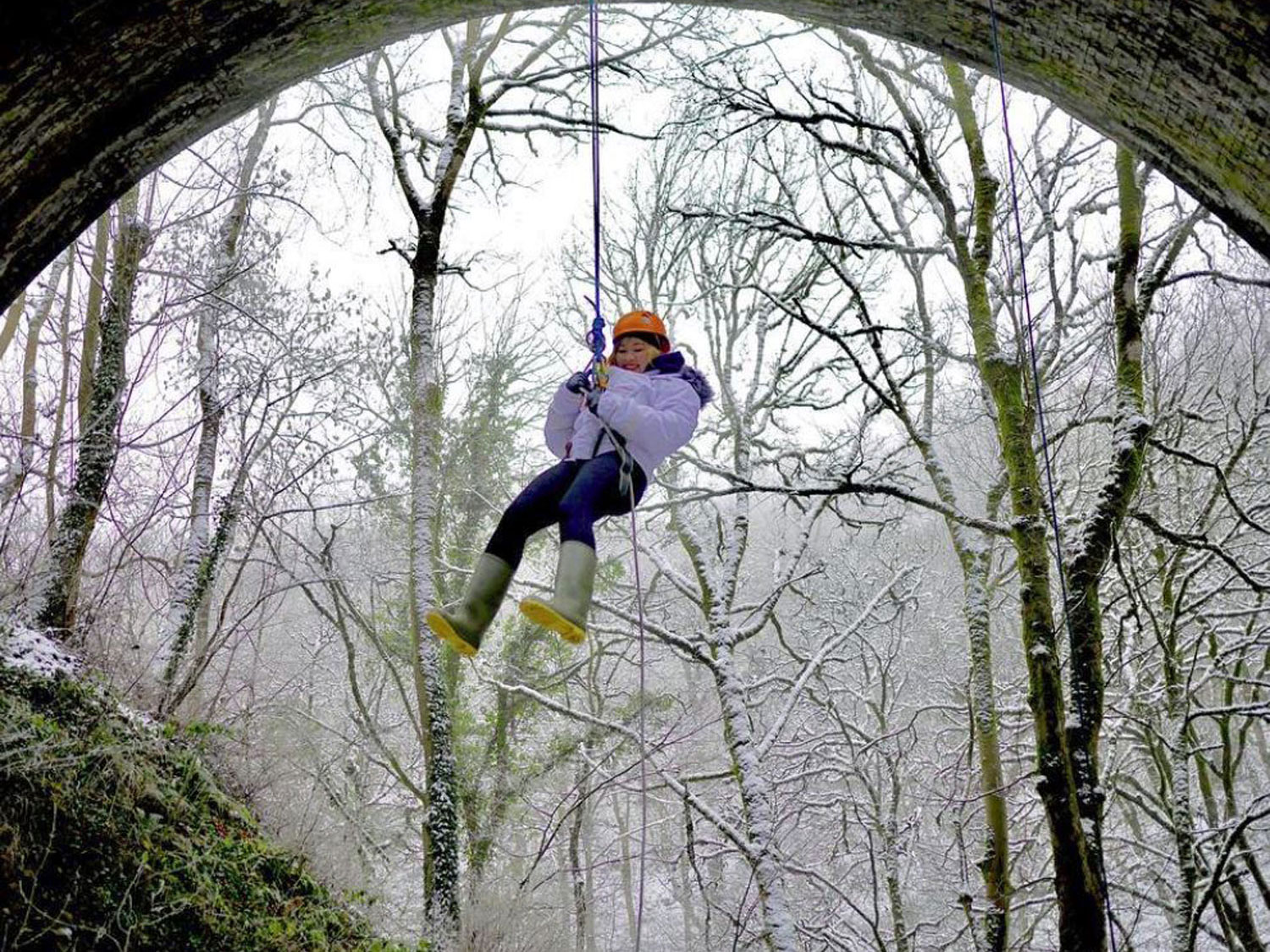 Guest abseiling from a bridge in winter